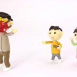 鬼のお面をかぶった人物と、豆を持ちながら豆まきをする2人の子どもの人形