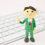 パソコンのキーボードの前で相続手続きのポイントを案内する人物の人形