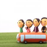 相続手続きをイメージした、家族4人と赤いバスのミニチュア